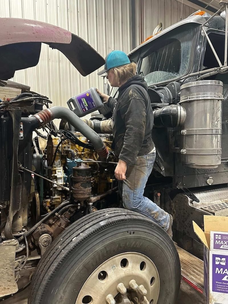 Technician adding fluid to a semi truck engine